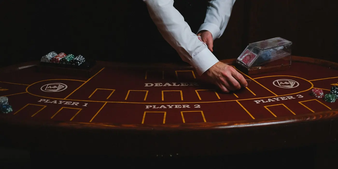 Mani di un croupier su un tavolo da gioco in penombra