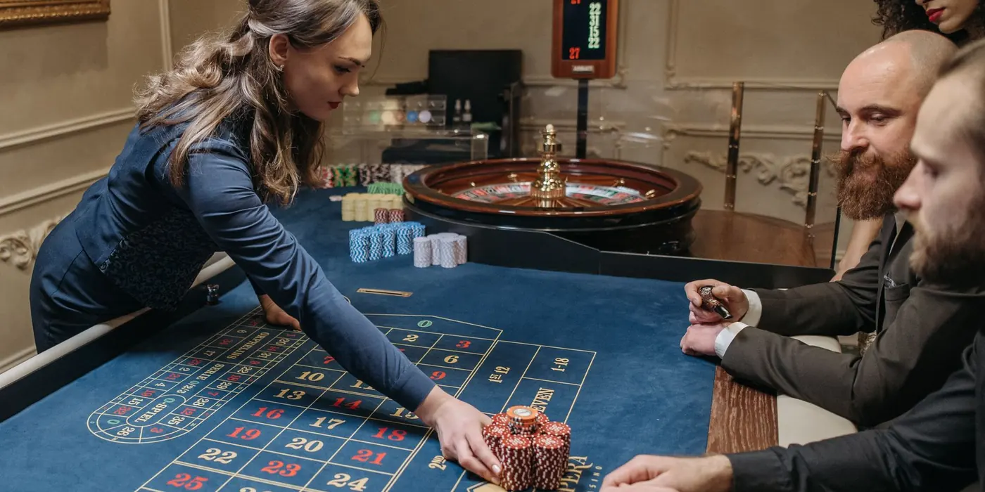 Una croupier sposta le fiches sul tappeto mentre i giocatori osservano